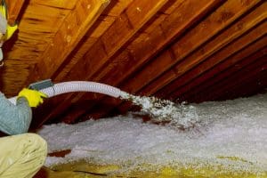 Technician spraying foam insulation in attic.