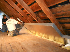 Two men installed the attic under the roof of the building.